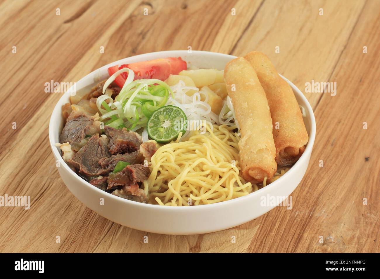 Soto Mie Bogor. Soupe traditionnelle de nouilles de bœuf Sundanese avec rouleau de printemps, chou et tomates. Street Food from Bogor, West Java, Indonésie. Isolé Banque D'Images