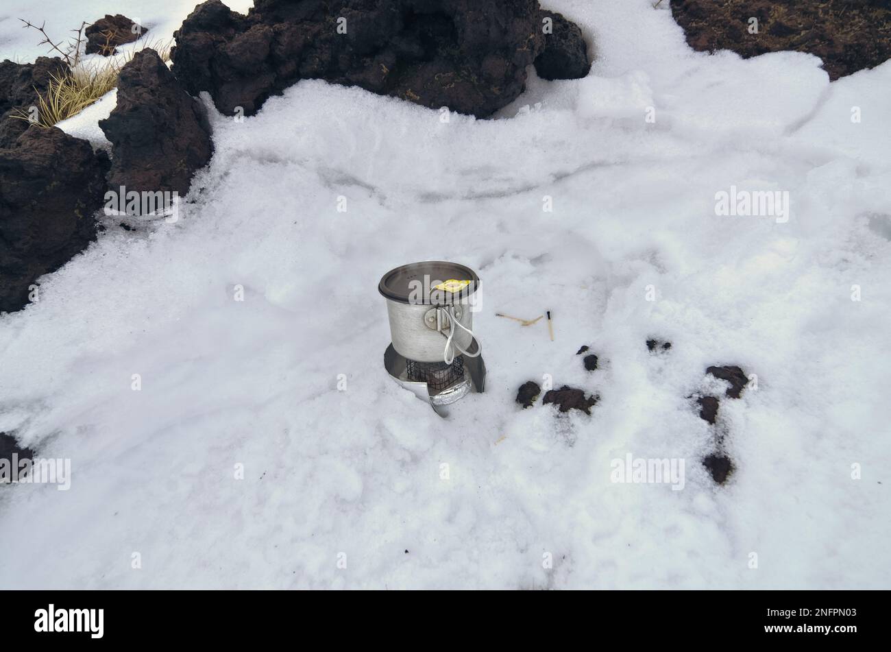 Sac à dos en métal avec couvercle sur le poêle à alcool de bricolage très basique et pare-brise sur la neige du parc national de l'Etna, Sicile, Italie Banque D'Images