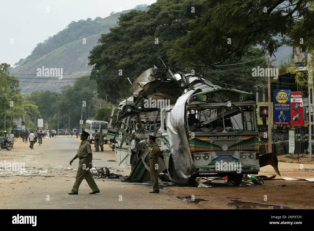 A Sri Lankan police officer stands guard at the site of a bus explosion as the wreckage of the bus is seen in the background, in Dambulla, about 150 kilometers (93 miles) northeast of Colombo, Sri Lanka, Saturday, Feb. 2, 2008. A bomb tore through the packed bus carrying civilians on Saturday in central Sri Lanka, killing some 20 people and wounding 50 others, the military said. (AP Photo/Eranga Jayawardena) Banque D'Images