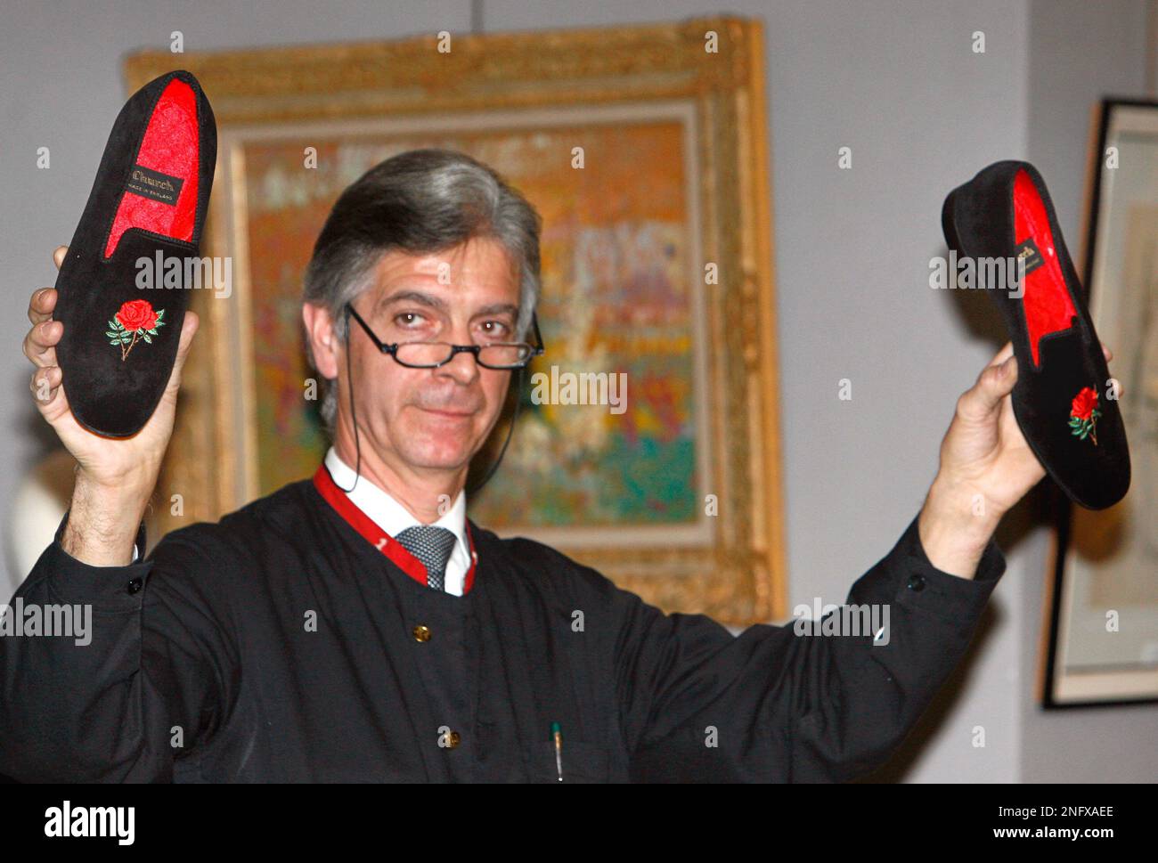 An auction house staff member holds a pair of French president Francois Mitterrand's slippers during an auction of the late French president's personal belongings at the Tajan auction house, in Paris on Tuesday, Jan. 29, 2008. The slippers were sold on for 550 euros ($800) . (AP Photo/Jacques Brinon) Banque D'Images