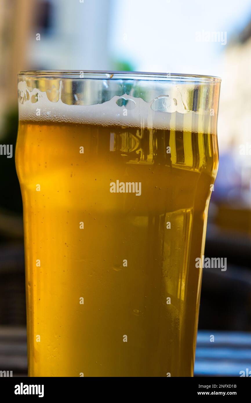 Verre de bière refroidi sur la table en bois. Un café de rue d'été flou à l'extérieur à l'arrière-plan Banque D'Images