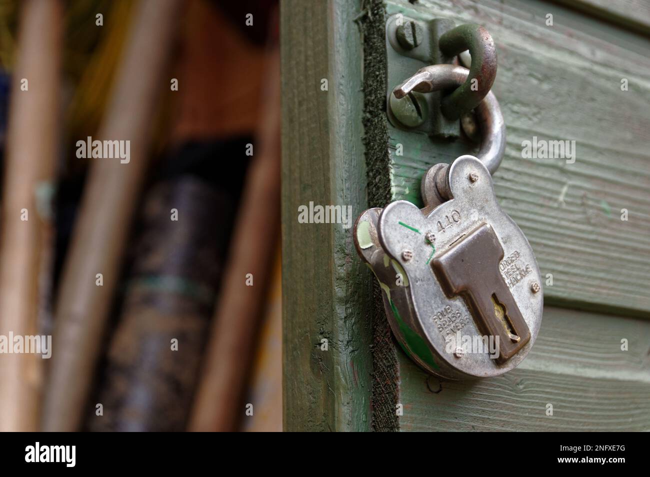 Un cadenas de style ancien, déverrouillé et suspendu sur un abri de jardin. La porte du hangar est ipen. Banque D'Images