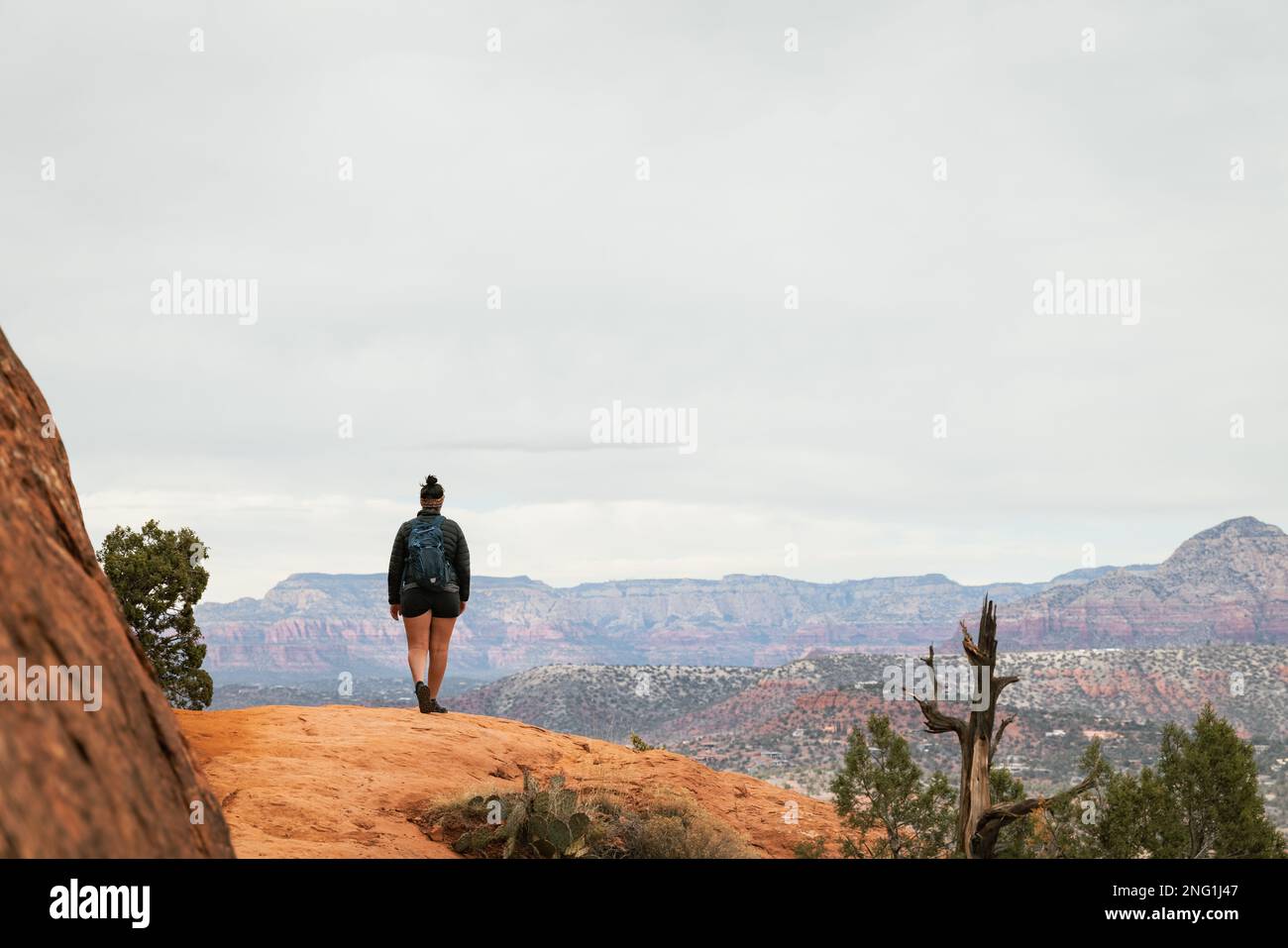 Femme randonneur se tenant sur le sentier Bell Rock dans les formations de roches rouges dans la forêt nationale de coconino à Sedona Arizona USA contre fond de nuages blancs. Banque D'Images