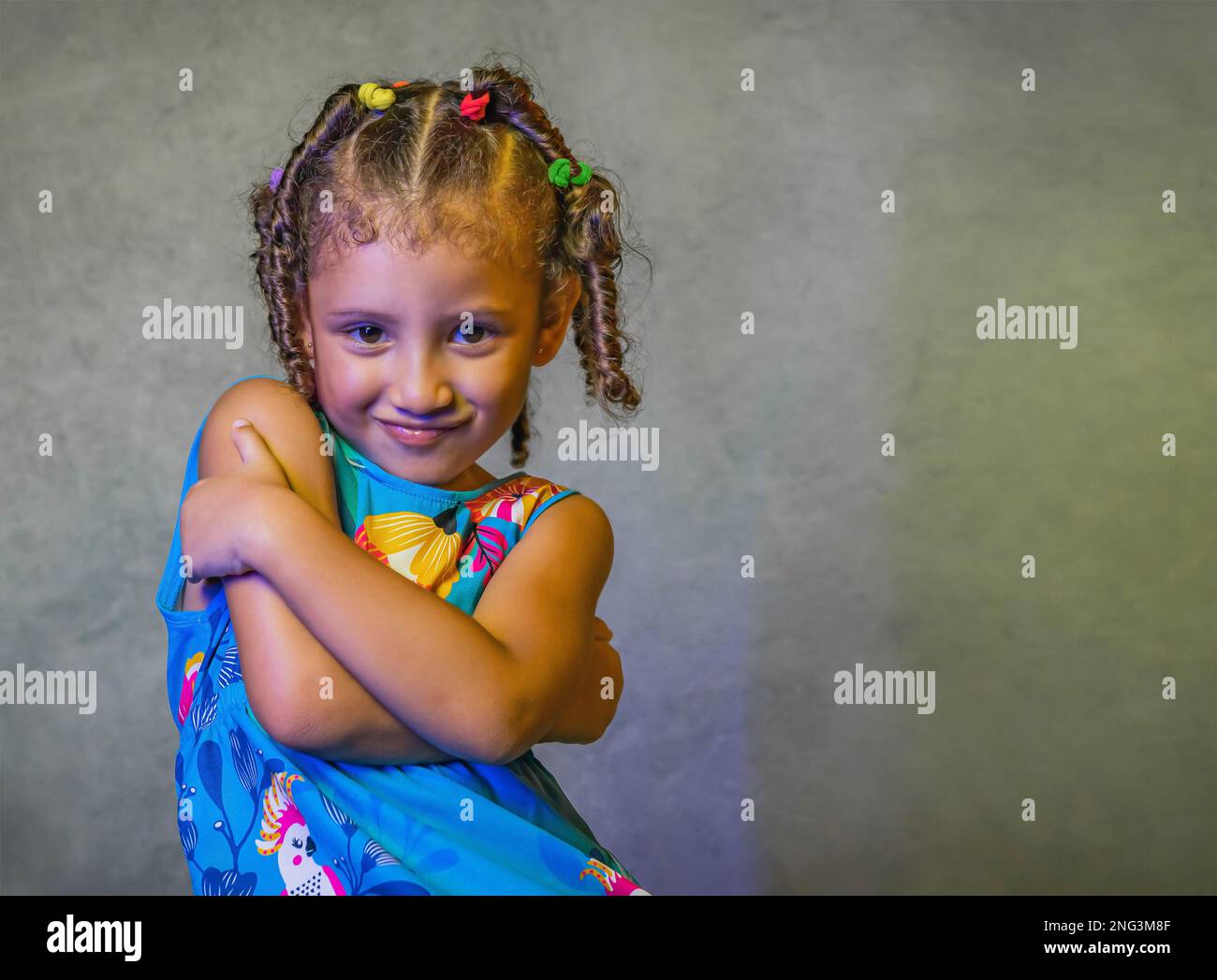 Studio portrait de belle petite fille dans la belle robe bleue sur fond violet, fille brésilienne souriant, donnant des baisers et faisant des visages drôles Banque D'Images