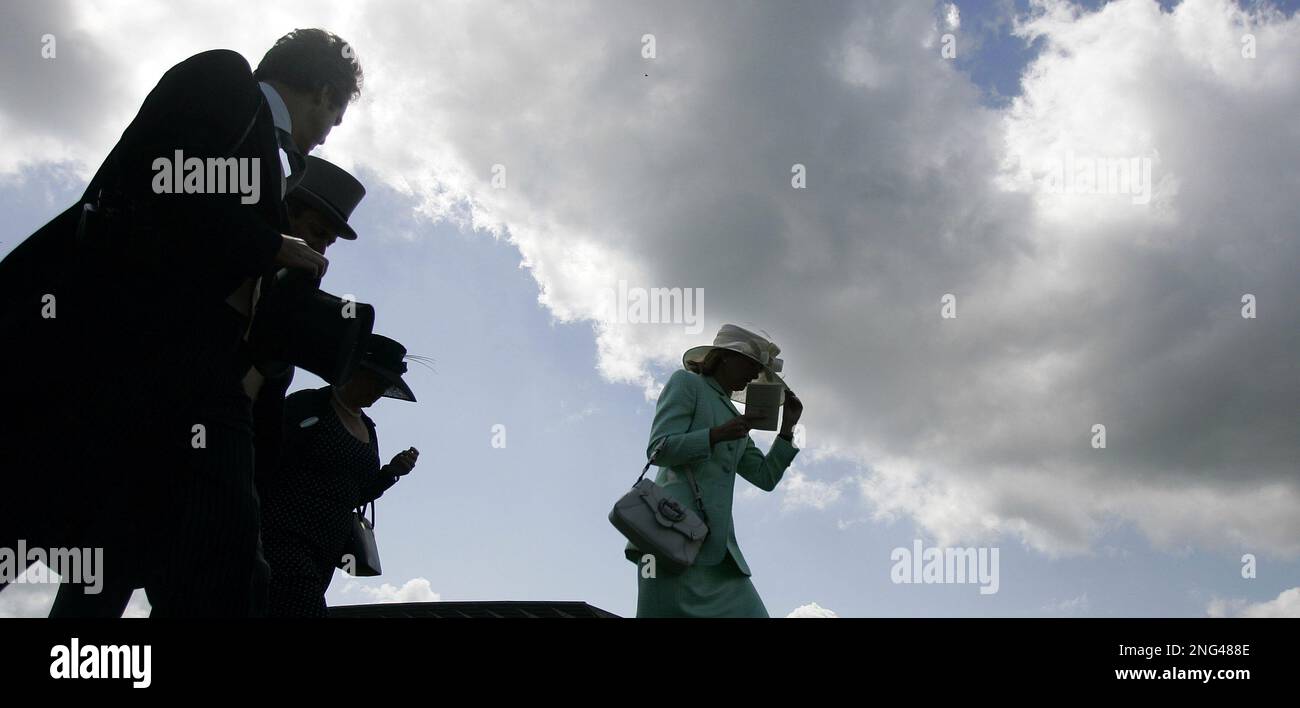 Early morning race goers walk across the track towards the main grandstand on the second day of the Royal Ascot horse racing meet at Ascot, England, Wednesday, June 20, 2007. Ascot is one of the highlights of the English social season, where fashion, especially hats, and horse racing mix. (AP Photo/Alastair Grant) Banque D'Images