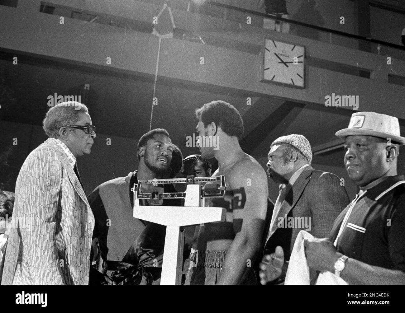 Heavyweight champion Joe Frazier, in front of scales, left, has a word with challenger George Foreman, in front of scales, right, during weigh-in at Kingston, Jamaica, Jan. 22, 1973. At left is Frazier's manager, Yank Durham, and representing Foreman is Archie Moore, second from right. (AP Photo) Banque D'Images