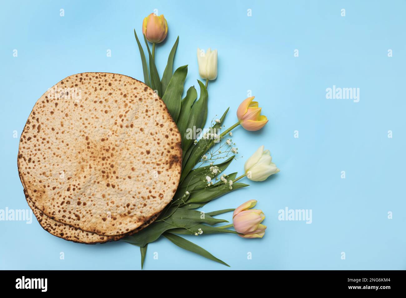 Savoureux matzos et fleurs fraîches sur fond bleu clair, plat. Fête de la Pâque (Pesach) Banque D'Images