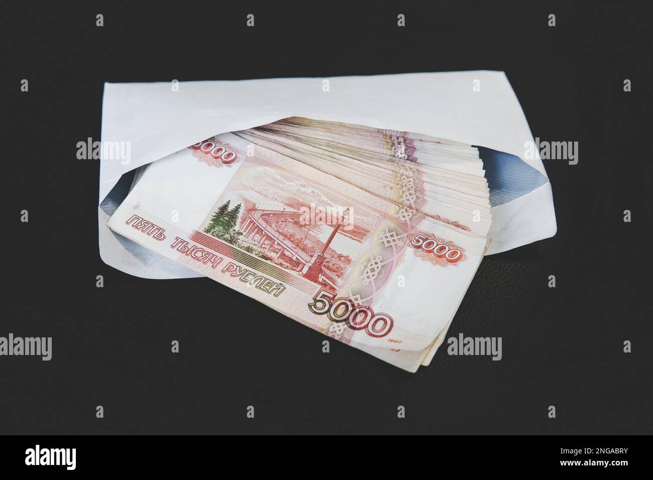 Grandes coupures de 5000 roubles dans une enveloppe blanche. Une main d'homme tient une enveloppe avec de l'argent. Le concept de corruption et de corruption Banque D'Images