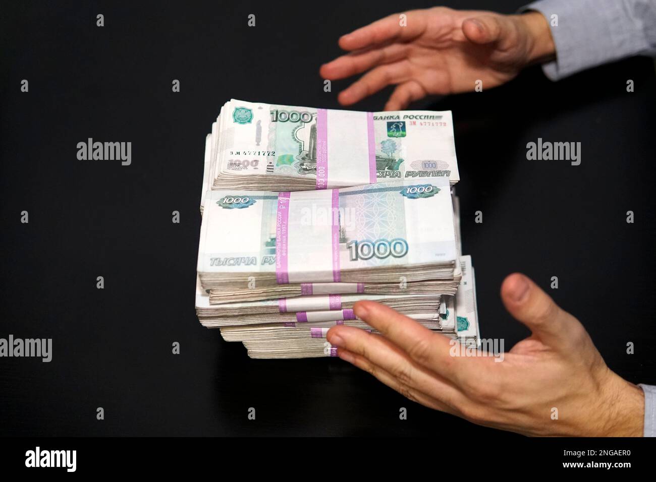 les mains des hommes atteignent un wad d'argent. Un million de roubles sur la table noire. Le concept de richesse et de réussite. Banque D'Images