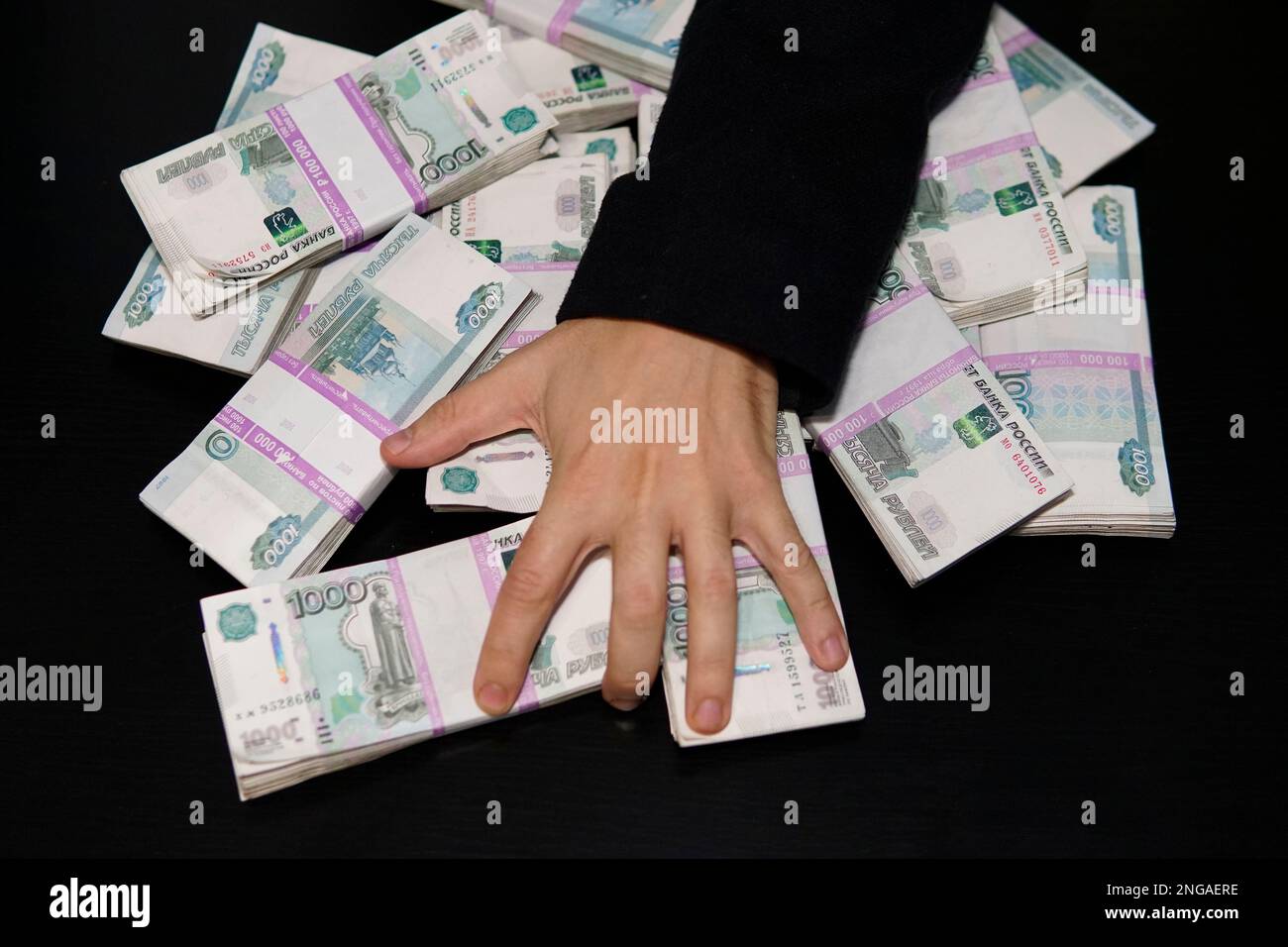 Les mains des hommes pour atteindre une liasse d'argent. Un million de roubles sur le tableau noir. Le concept de la richesse, le succès, la cupidité et la corruption, la soif de l'argent Banque D'Images