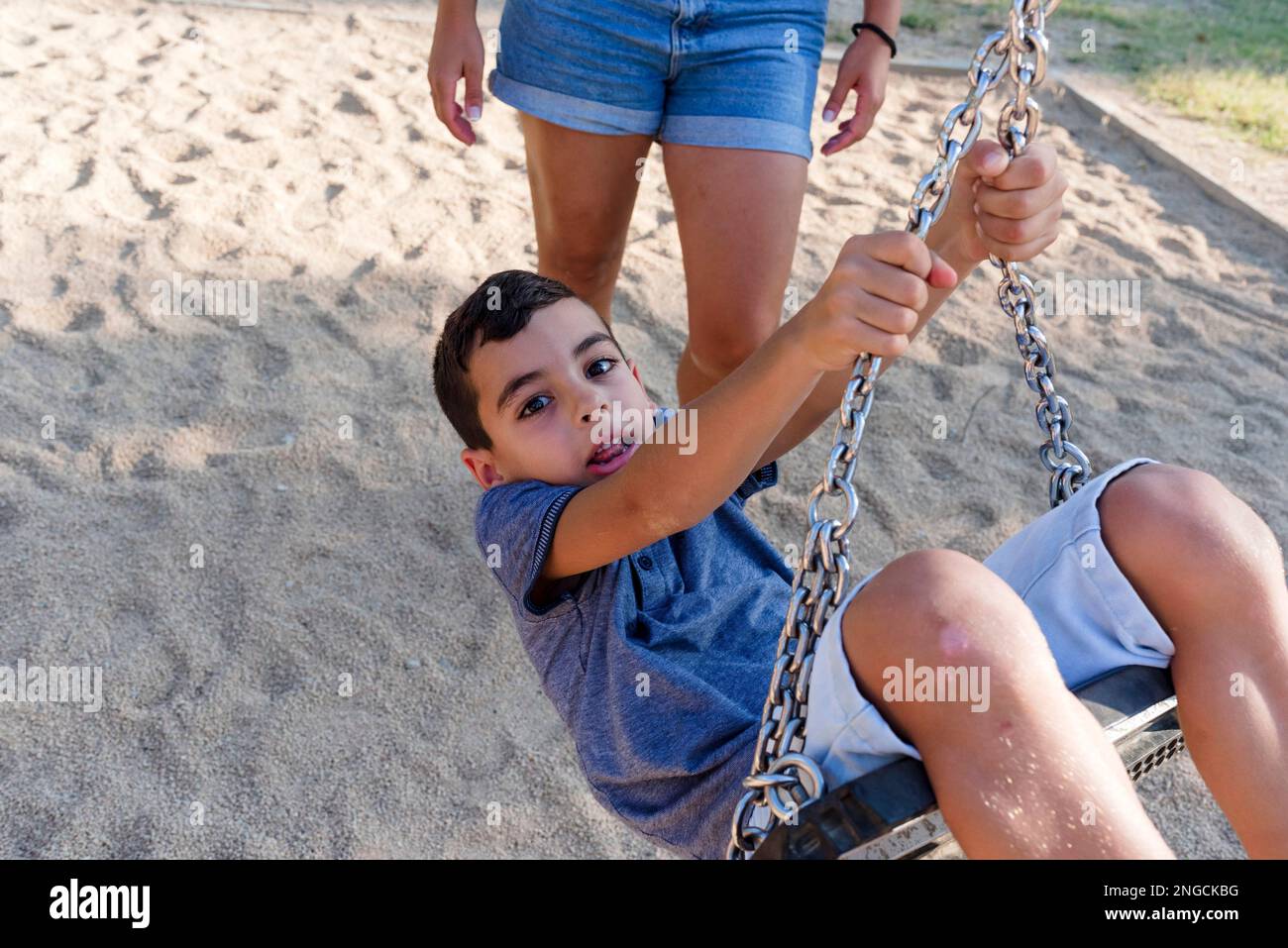 Mère et fils s'amusant à jouer avec l'oscillation dans un parc. Banque D'Images