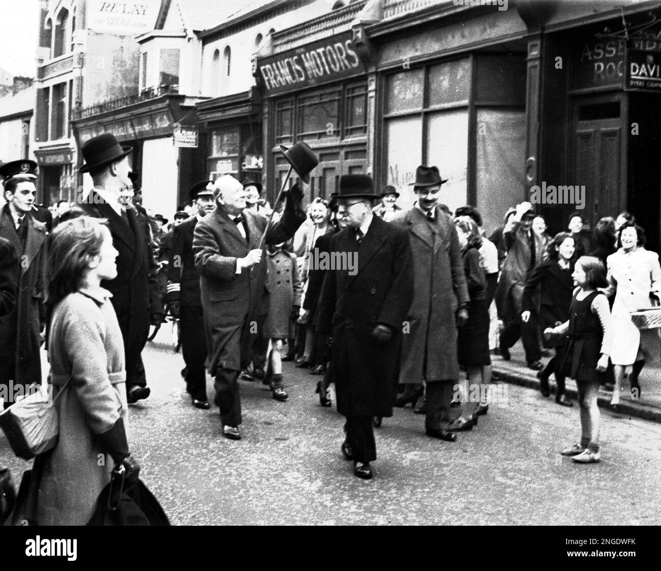 Britain's Prime Minister Winston Churchill hoists his famous 'John Bull' hat on to his walking stick and waves it in recognition of the crowd's cheers on a tour of Swansea, in south Wales, in April 1941. (AP Photo/British Official Photo) Banque D'Images