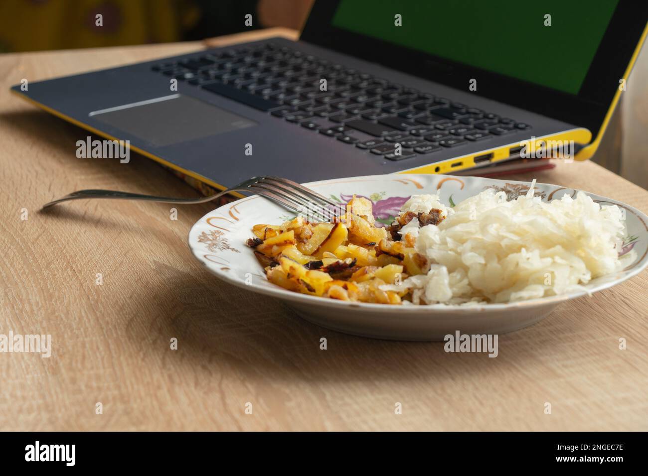 pommes de terre frites au chou dans une assiette près de l'ordinateur portable Banque D'Images