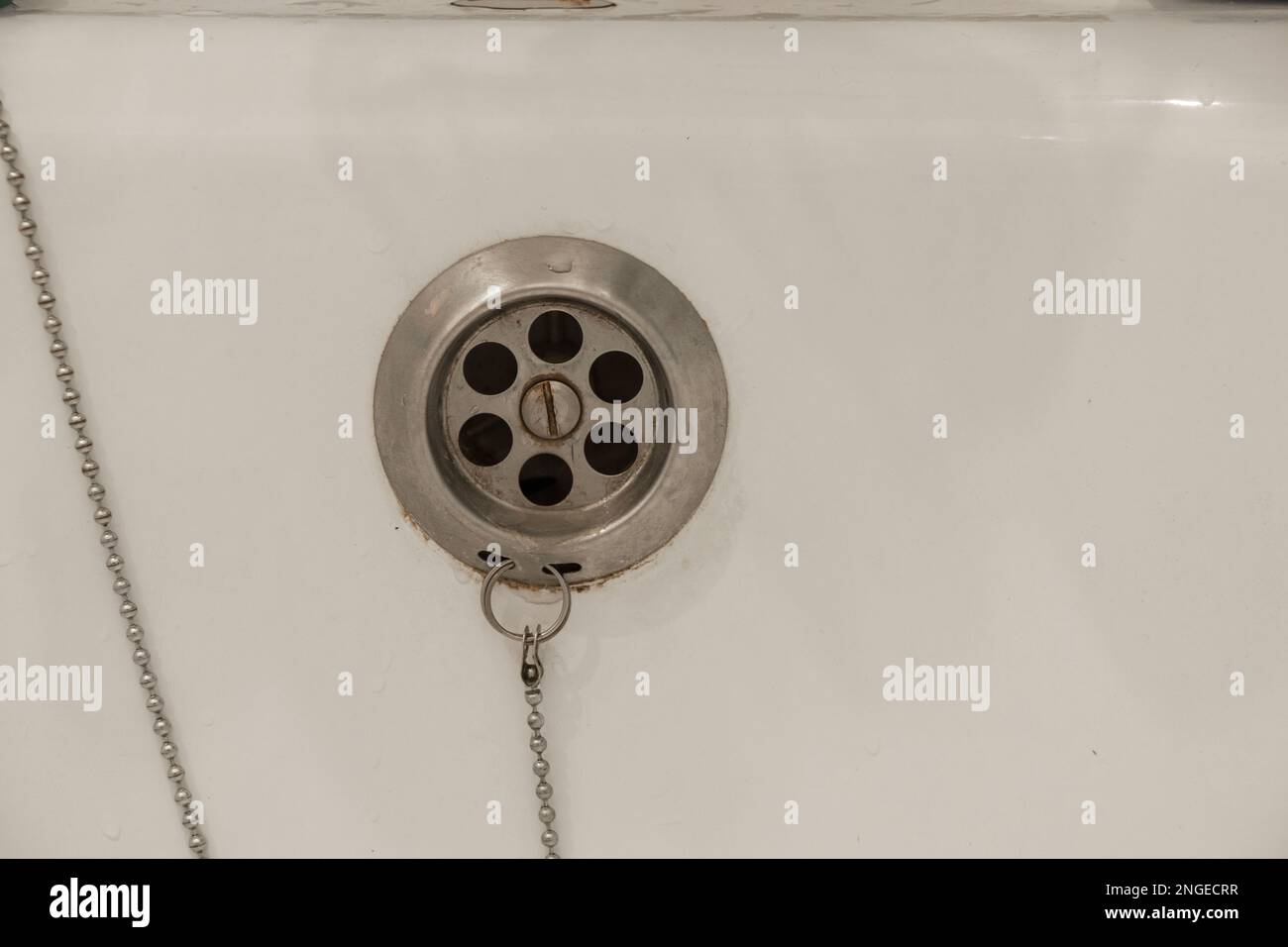 Eau de drainage avec bouchon en caoutchouc de drainage sur la baignoire de douche blanche de près Banque D'Images