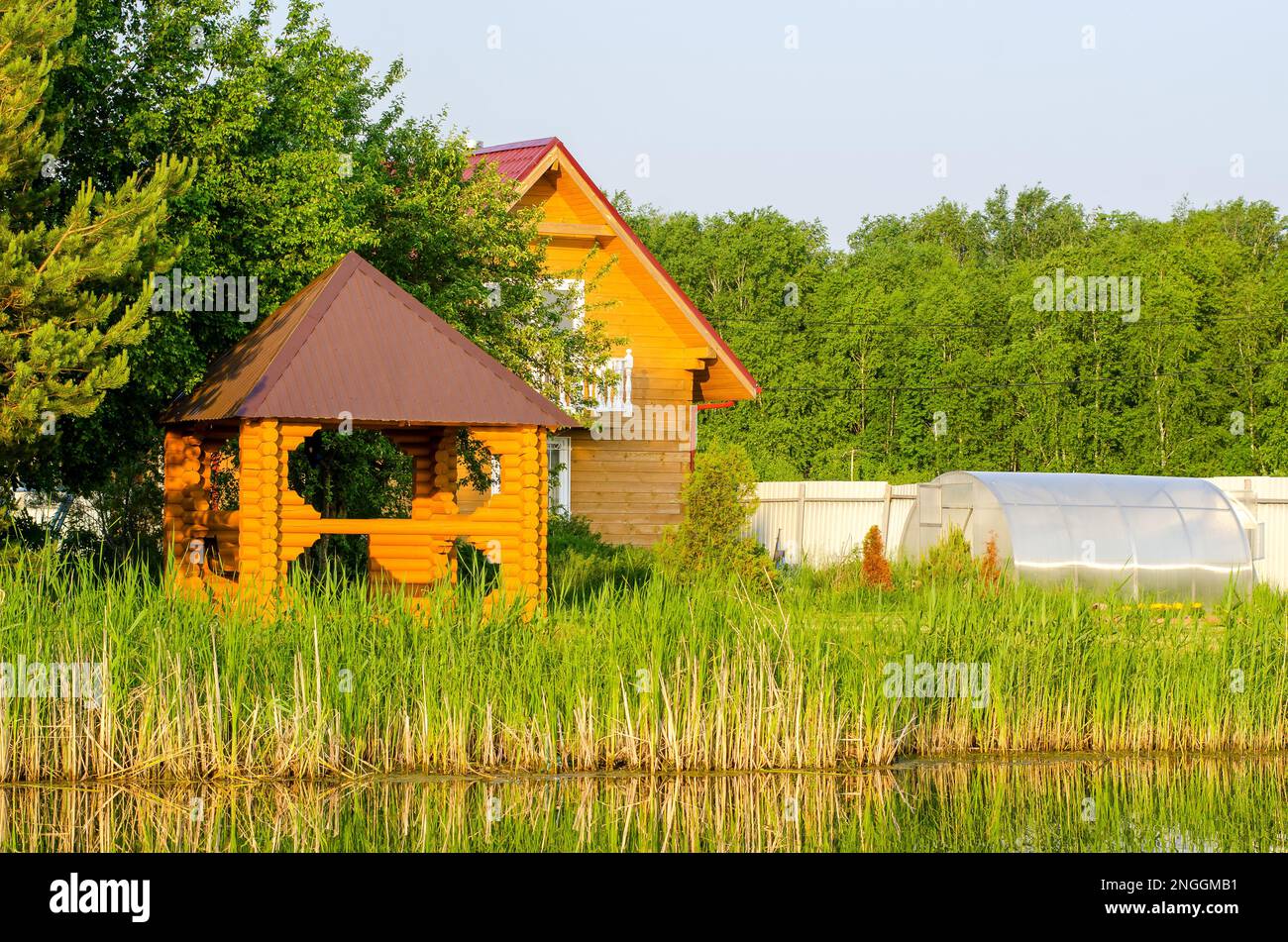 Jardins avec des chalets et un belvédère pour se détendre sur la rive d'un petit lac en Sibérie en été au milieu de l'herbe. Banque D'Images