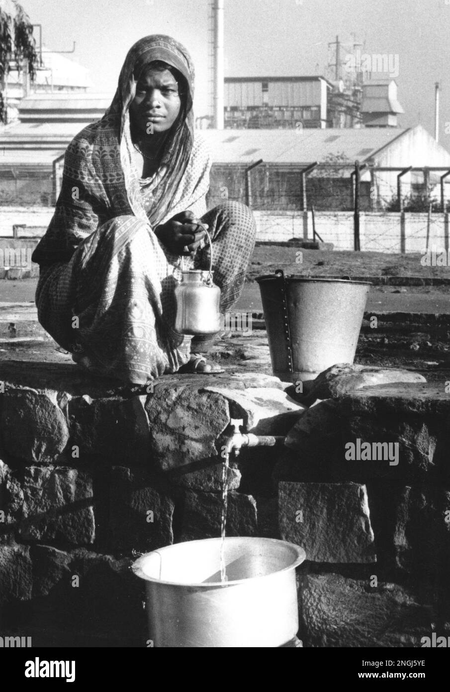 A woman who lives in a nearby slum is shown collecting water in front of the Union Carbide plant