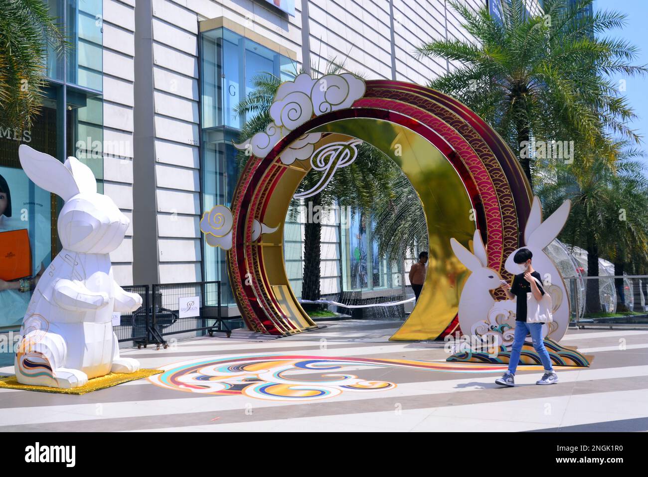 Une personne passe devant une exposition chinoise du nouvel an avec des statues de lapins et une arche colorée à l'extérieur du centre commercial ou du centre commercial Siam Paragon, Bangkok, Thaïlande, Asie. Selon le zodiaque chinois, 2023 est l'année du lapin. Banque D'Images