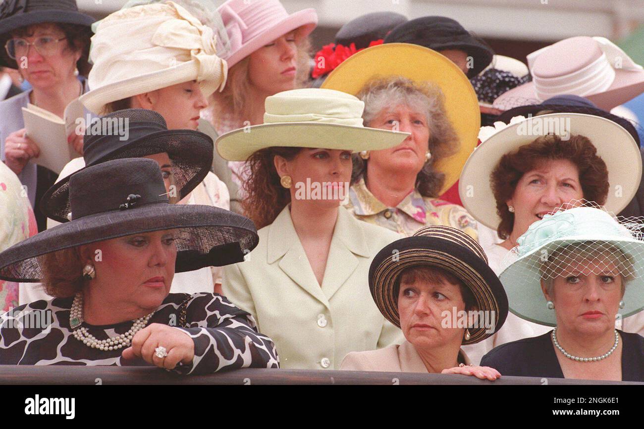Women racegoers in a selection of hats, wait to catch a glimpse of Britain's Queen Elizabeth II at the Royal Ascot horse race meeting at Ascot, England, Thursday June 20, 1996. Cold and wet weather replaced sunglasses on Ladies Day - traditionally the day when the most colourful and outrageous fashions are worn - at the meeting, which is one of the highlights of the British social season.(AP Photo/Louisa Buller) Banque D'Images
