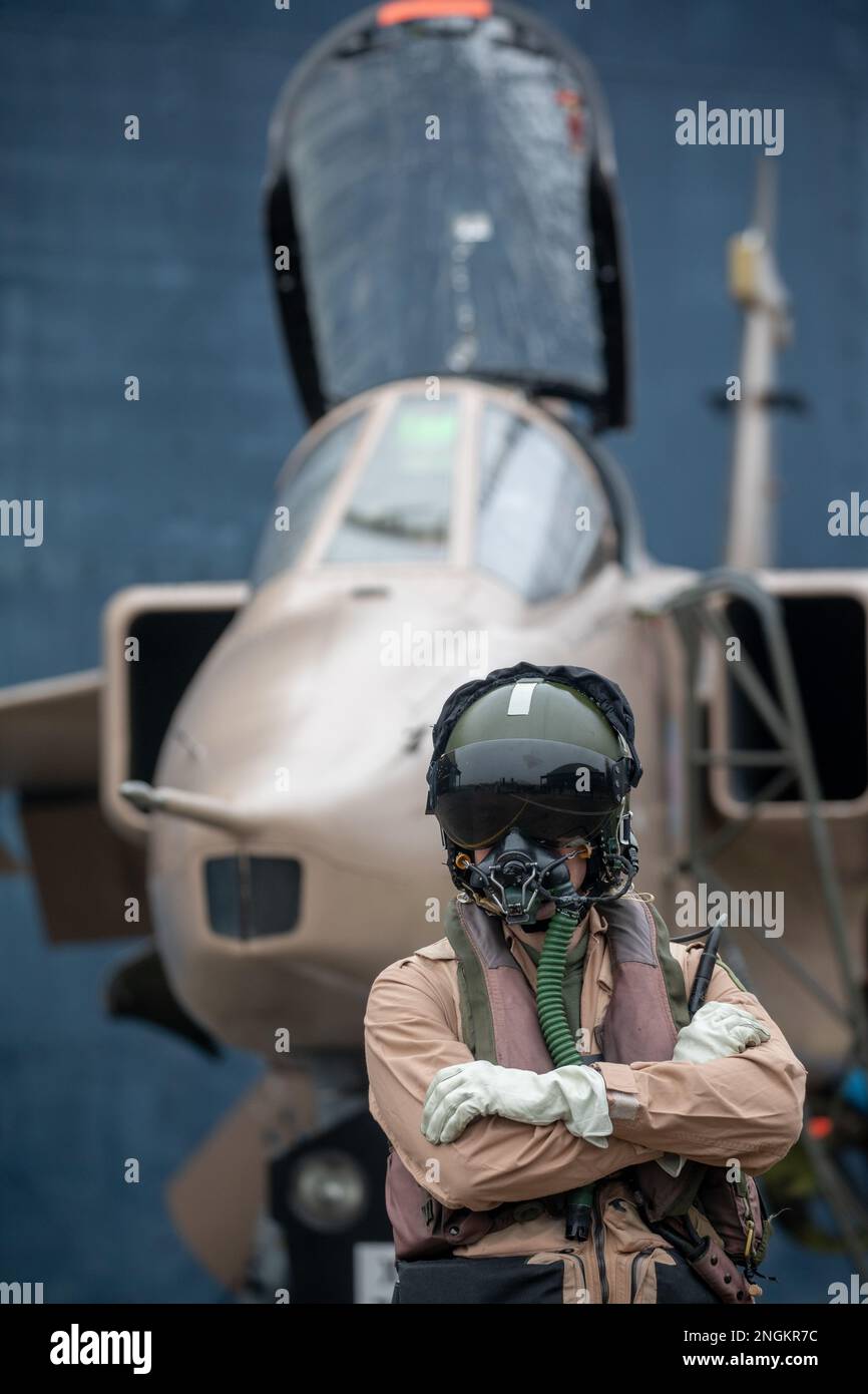 Pilote de chasse, RAF, debout avec Fighter Jet prêt pour une mission de combat portant casque volant, costume et visière sombre avec masque à oxygène Royal Air Force. Banque D'Images