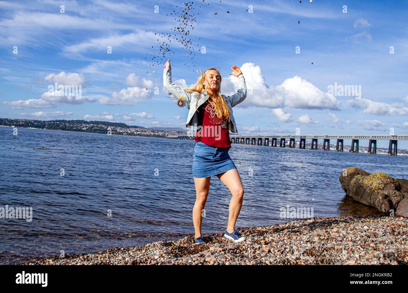 Lors d'une belle journée d'octobre à Wormit Beach, Fife, Rhianna Martin jette des cailloux sur sa tête dans la rivière Tay, en Écosse Banque D'Images