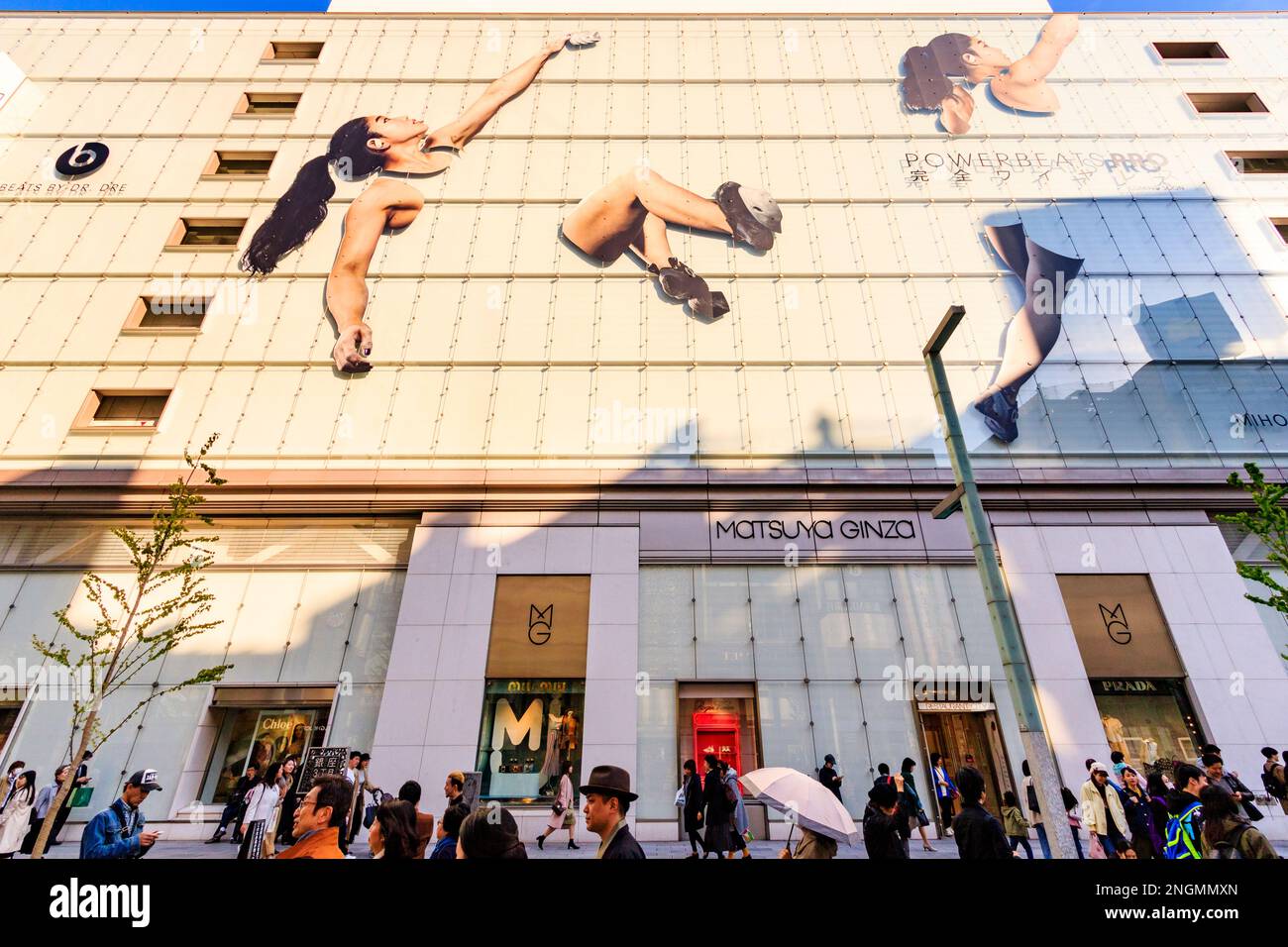 Sur la chaussée, regardant le magasin Matsuya Ginza avec sa façade en verre vert avec Écouteurs powerbeats pro display. Heure d'or. Banque D'Images