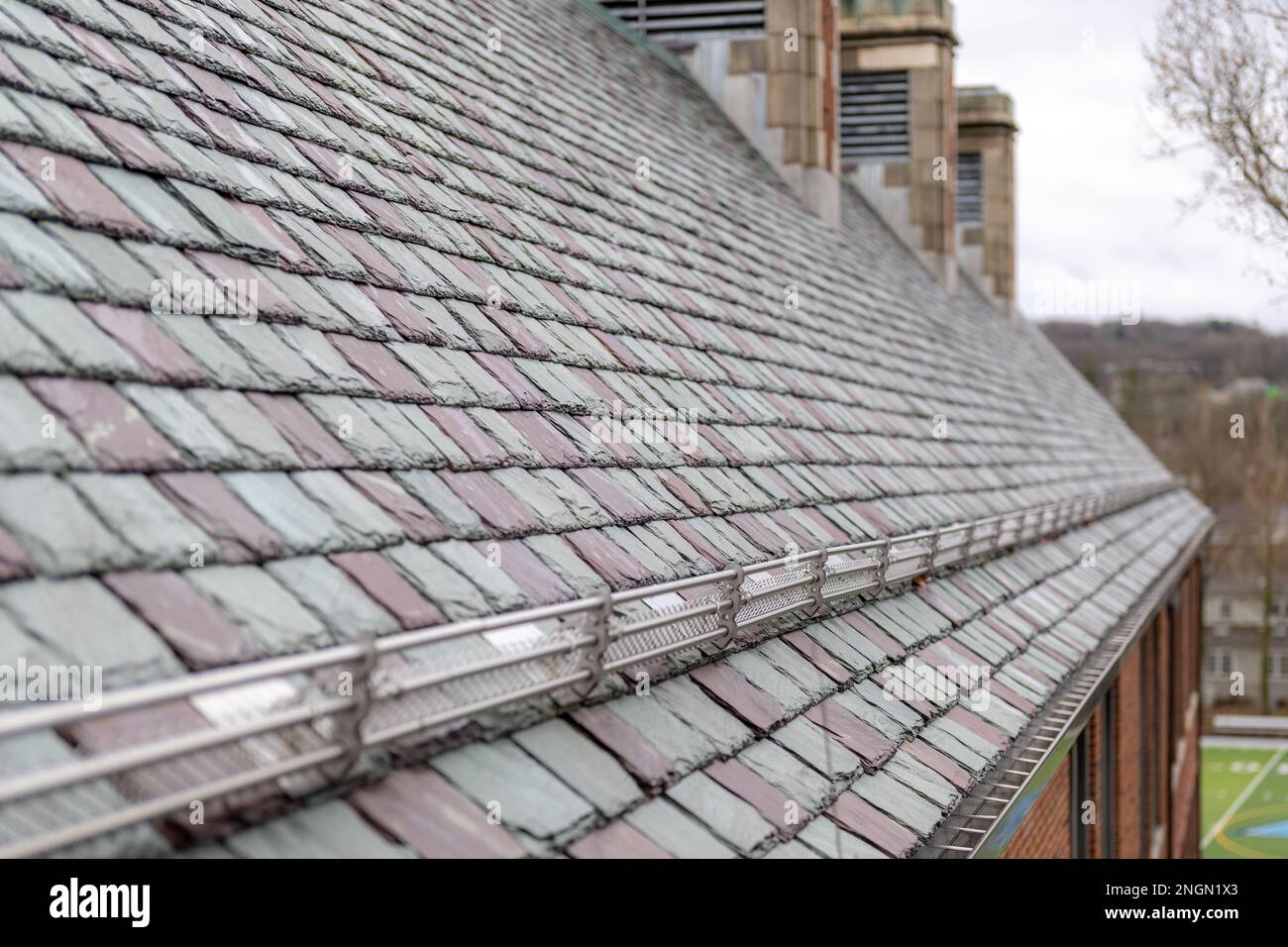 Tuiles de toiture en ardoise avec neige et garde-glace sur un bâtiment historique. Matériau de couverture attrayant et durable. Banque D'Images