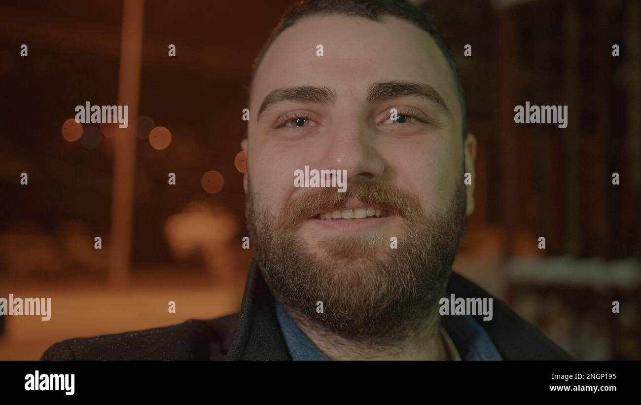 Homme barbu effectuant un appel vidéo par temps de neige tout en souriant à la caméra Banque D'Images