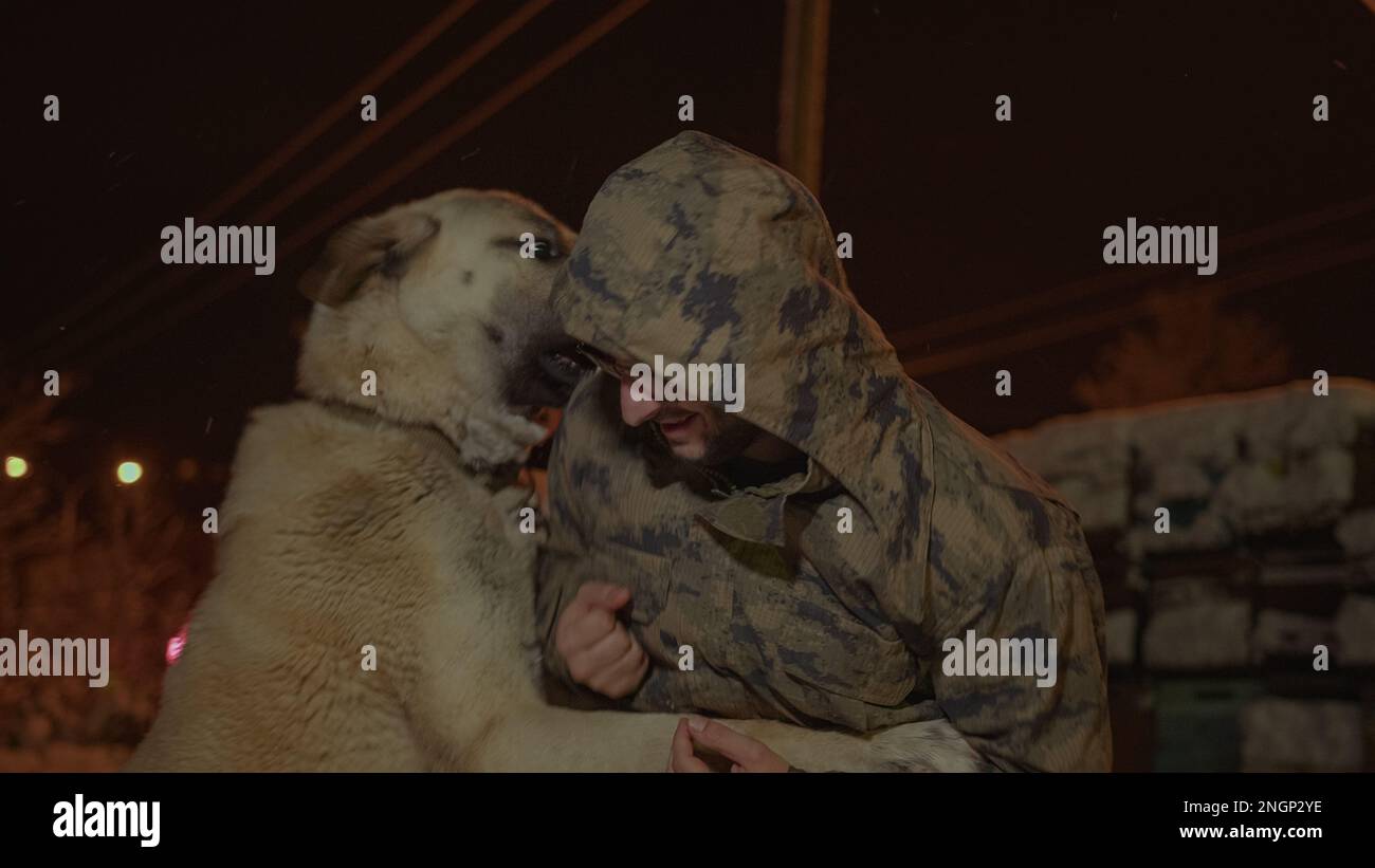 Militaire-Clad Jeune Homme jouant avec un chien Sivas Kangal dans le temps de neige Banque D'Images