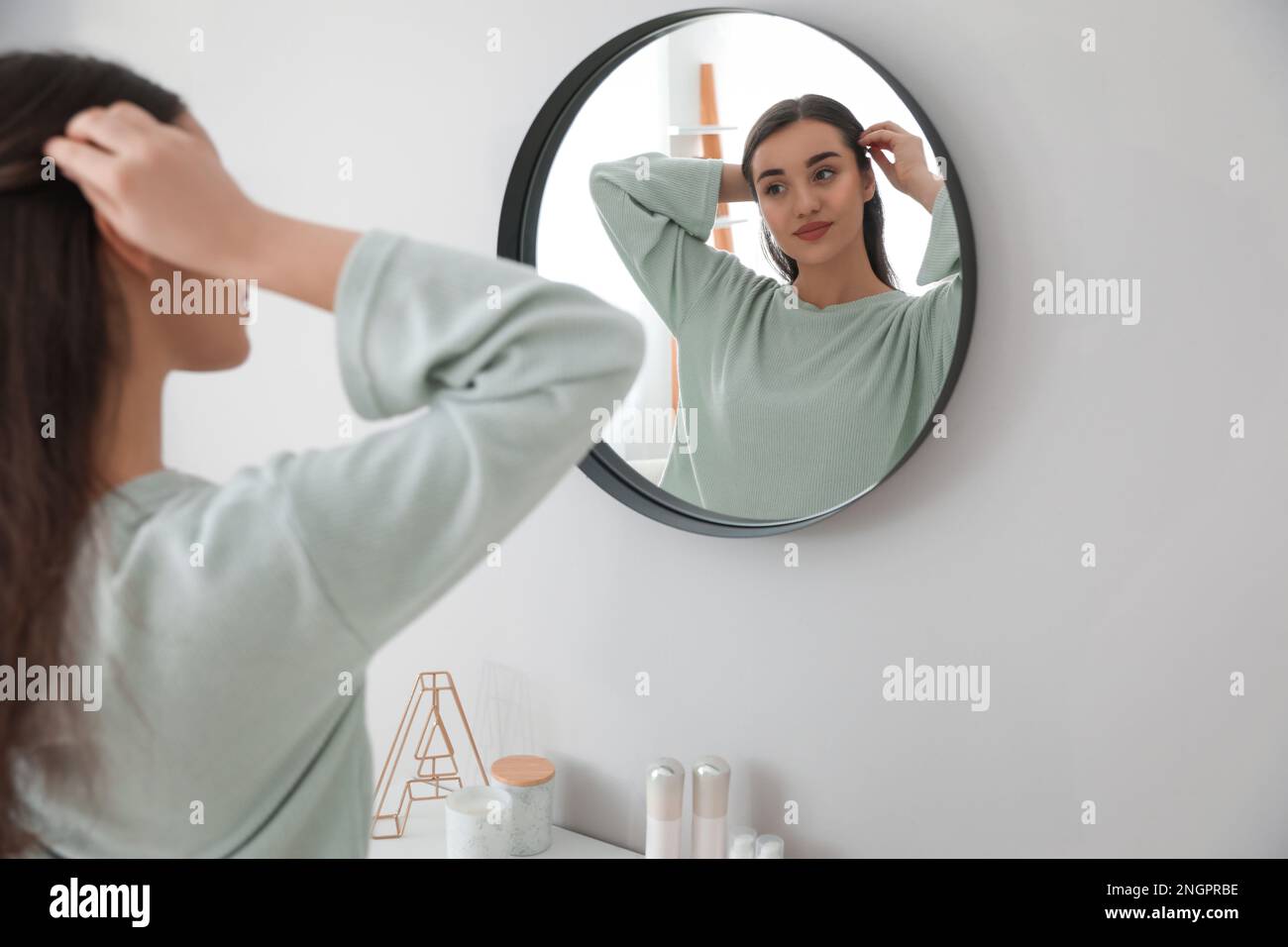 Jeune femme faisant les cheveux près du miroir à la maison. Routine du matin Banque D'Images