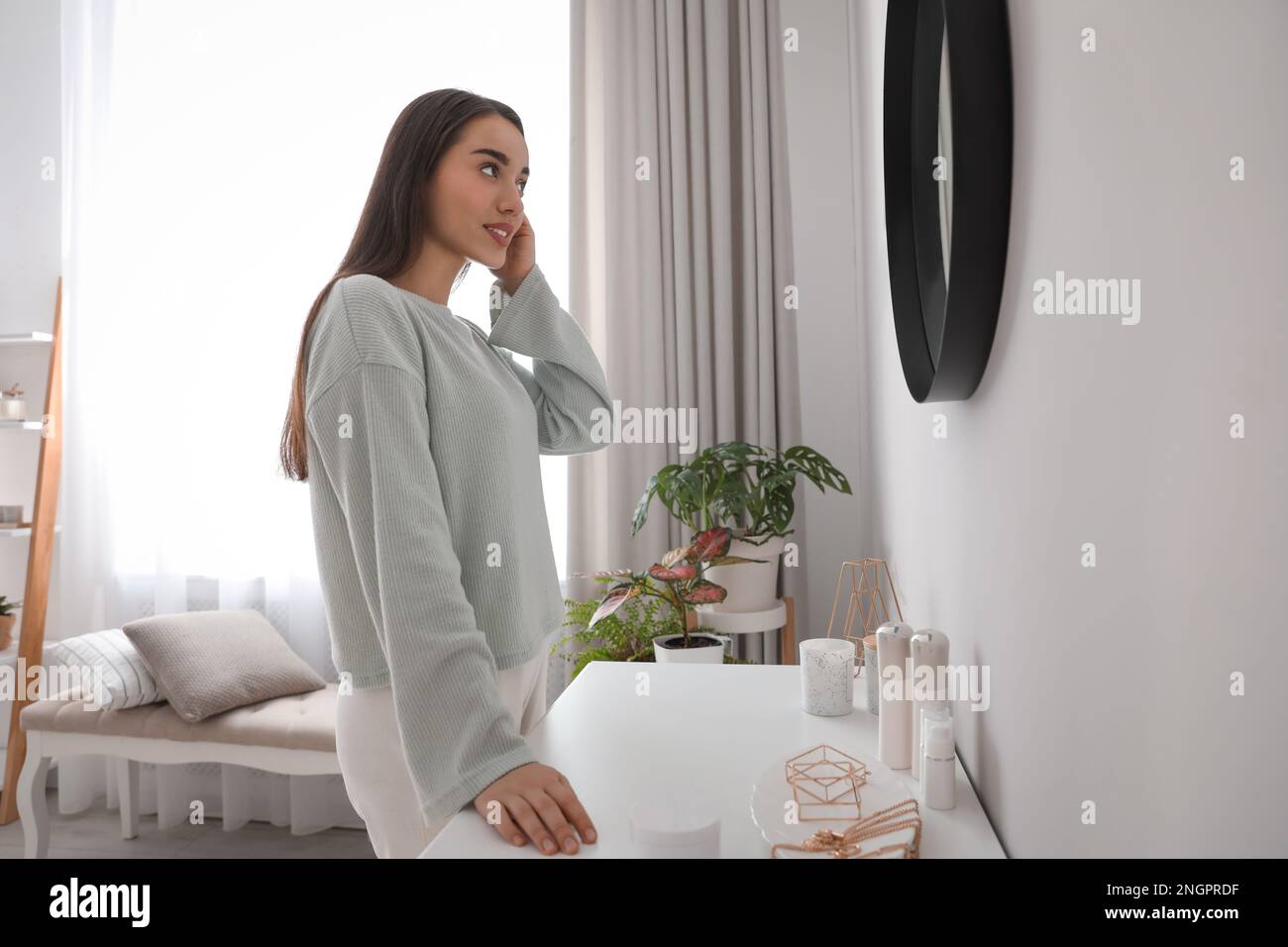 Jeune femme faisant les cheveux près du miroir à la maison. Routine du matin Banque D'Images