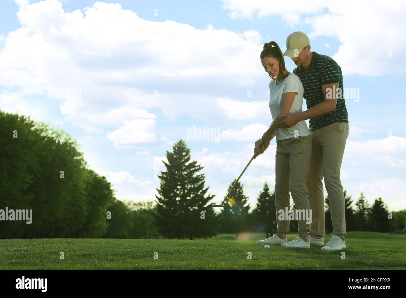 Homme enseignant à sa petite amie de jouer au golf sur le green course Banque D'Images