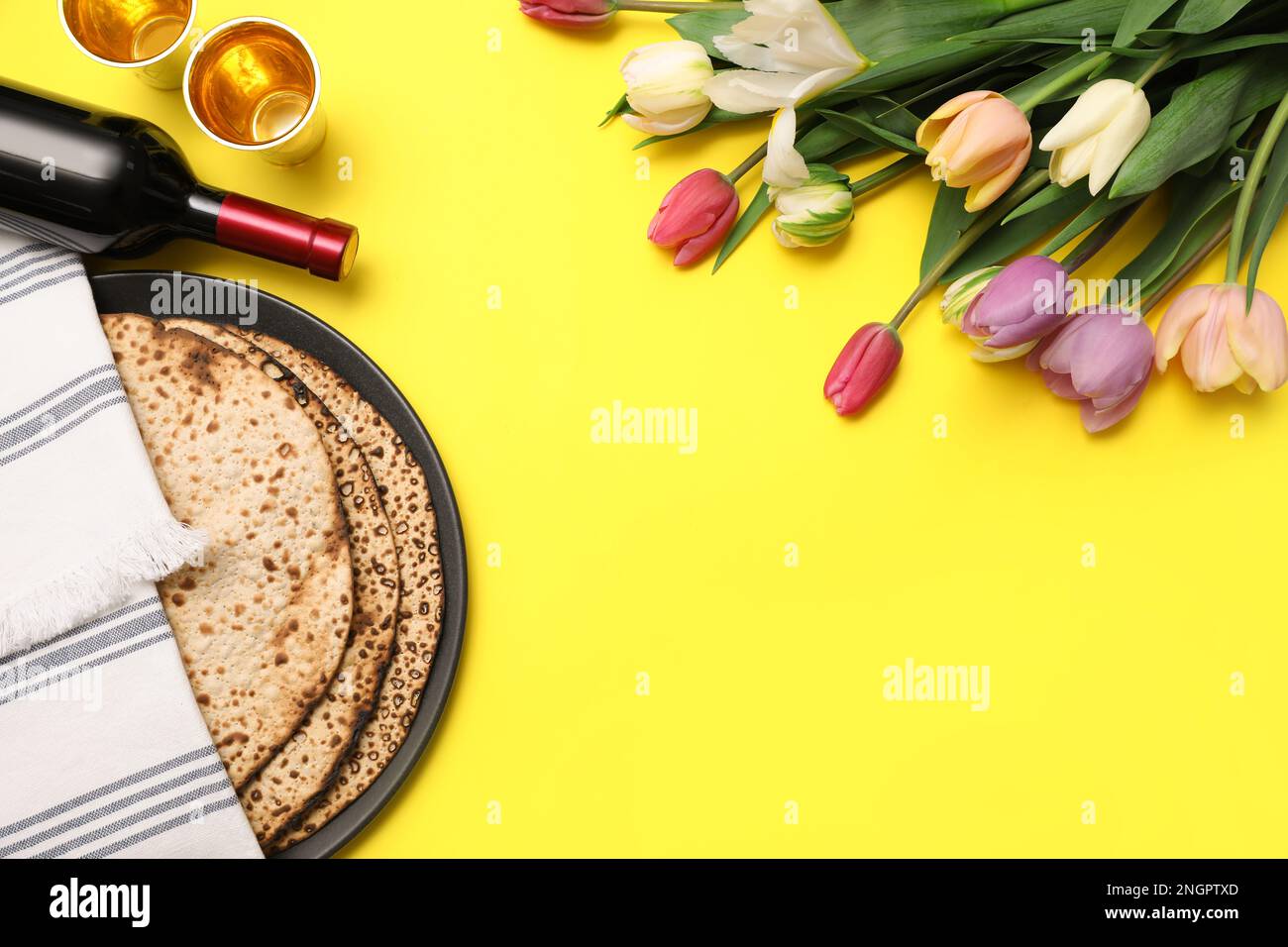 Savoureux matzos, vin et fleurs fraîches sur fond jaune, espace pour le texte. Fête de la Pâque (Pesach) Banque D'Images