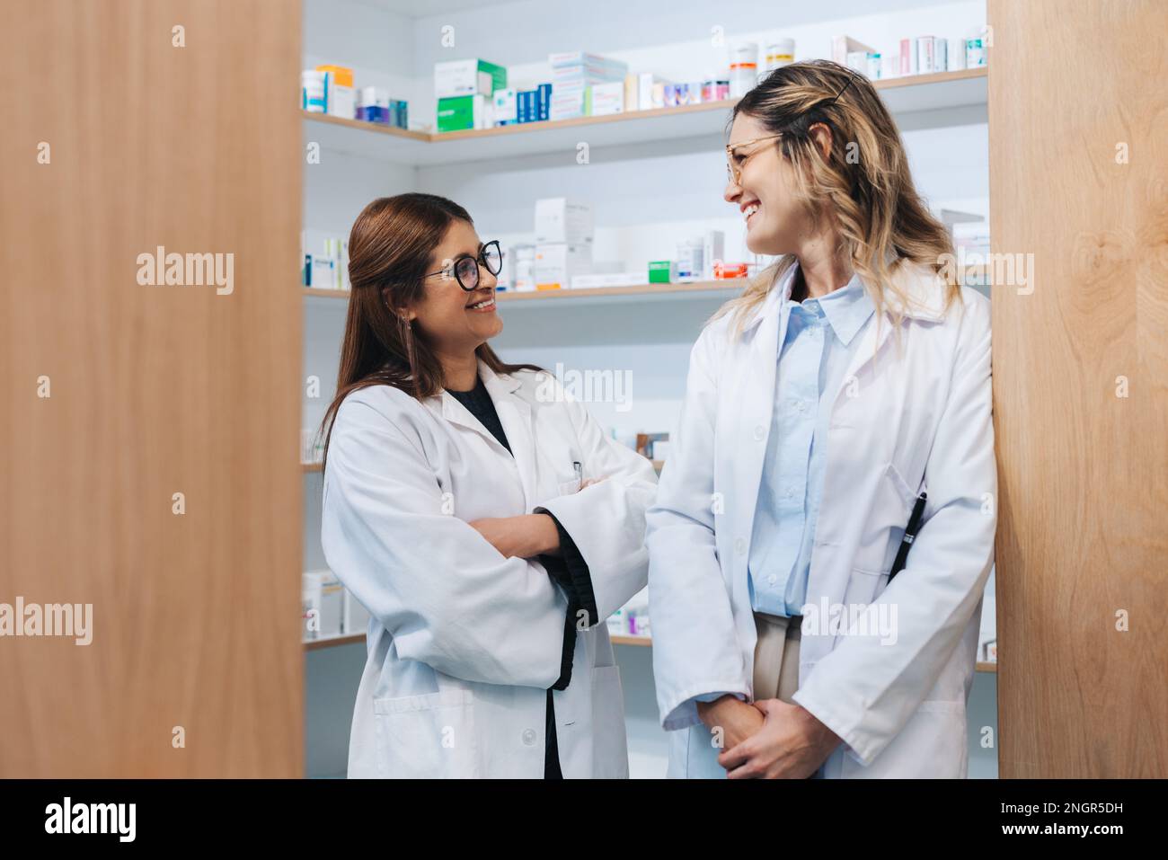 Deux femmes pharmaciens debout dans un magasin de drogue et souriant l'une à l'autre. Des professionnels de santé heureux travaillant ensemble dans une pharmacie. Banque D'Images