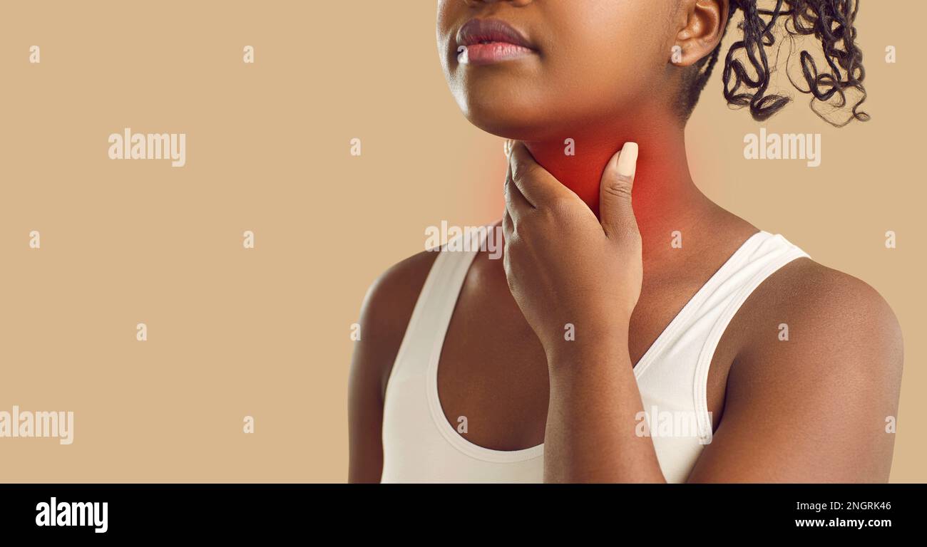 Inconnue jeune femme à la peau foncée tenant sa gorge sur fond beige. Bannière. Banque D'Images