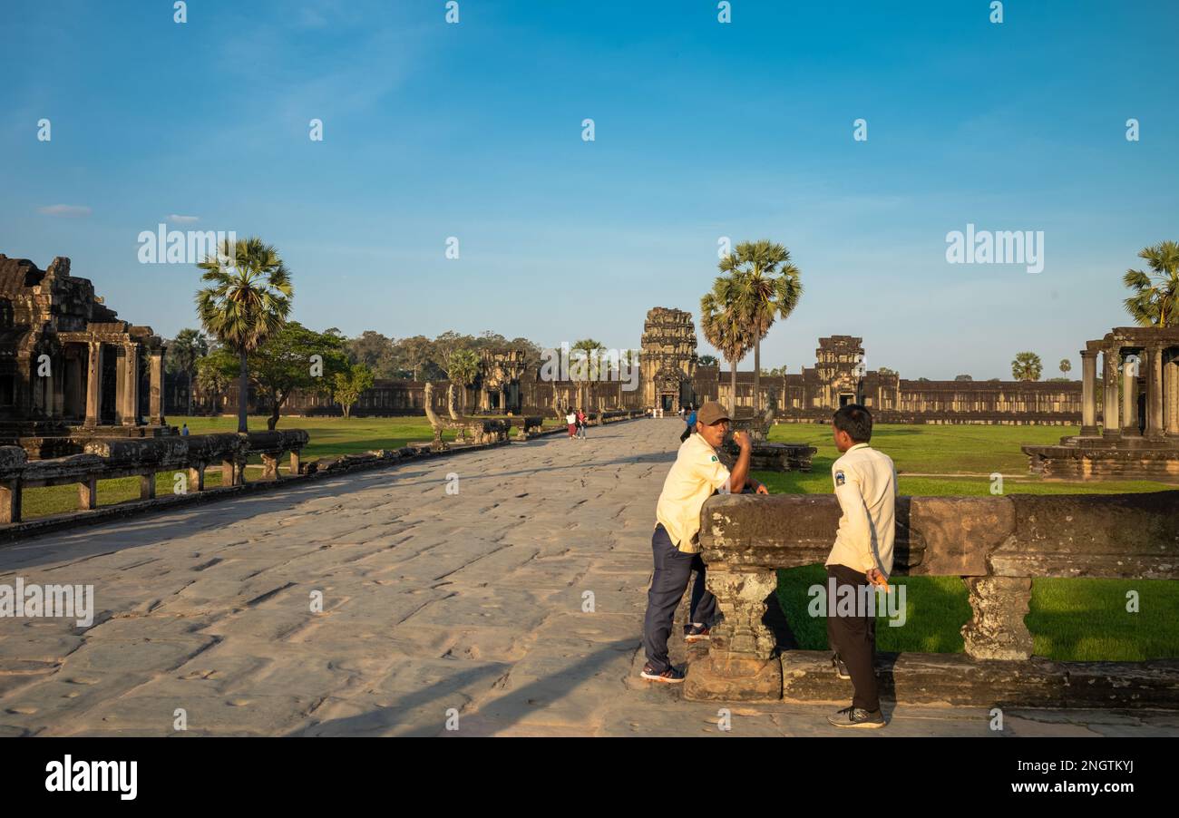 Deux guides touristiques officiels discutent sur la chaussée de la porte Ouest au célèbre temple antique d'Angkor Wat au Cambodge Banque D'Images
