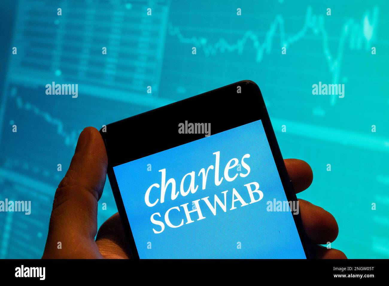 Dans cette illustration, le logo de la société multinationale américaine de services financiers Charles Schwab est affiché sur un smartphone avec un graphique d'indice boursier économique en arrière-plan. Banque D'Images