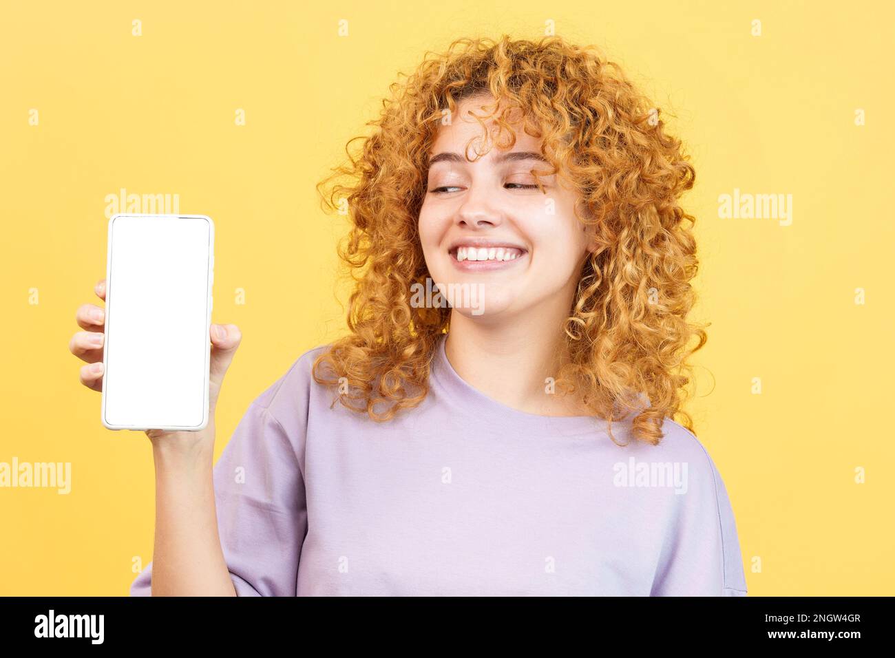 Femme souriante montrant l'écran vide du mobile Banque D'Images