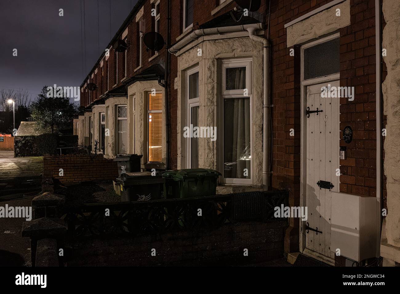 Rue de maisons mitoyennes de classe moyenne/classe ouvrière avec voitures garées dans la rue de la banlieue de Cardiff la nuit Banque D'Images