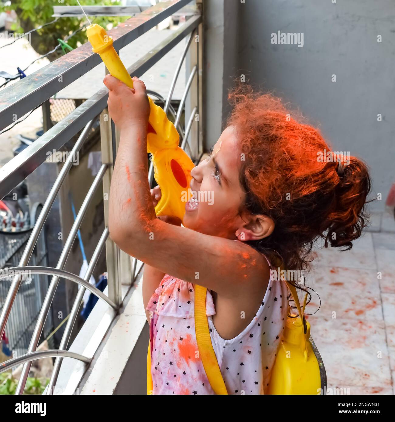 Douce petite fille indienne jouant des couleurs sur le festival Holi, tenant la pichakaree pleine de couleurs, les célébrations du festival Holi à Delhi, Inde. Banque D'Images