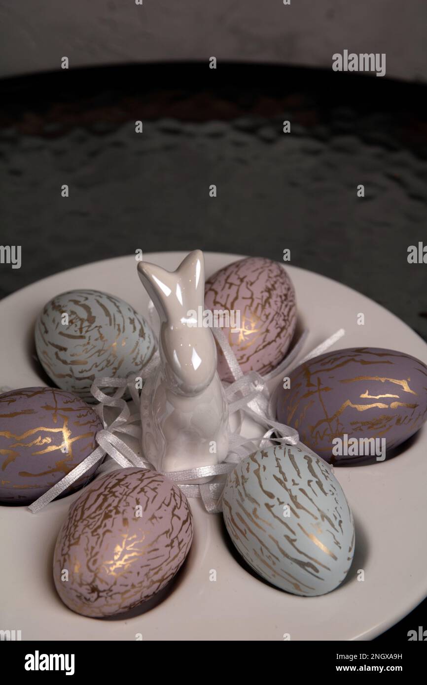 photo des oeufs décoratifs dans une assiette spéciale pour les oeufs et les stands de figurine de lapin blanc sur la table Banque D'Images