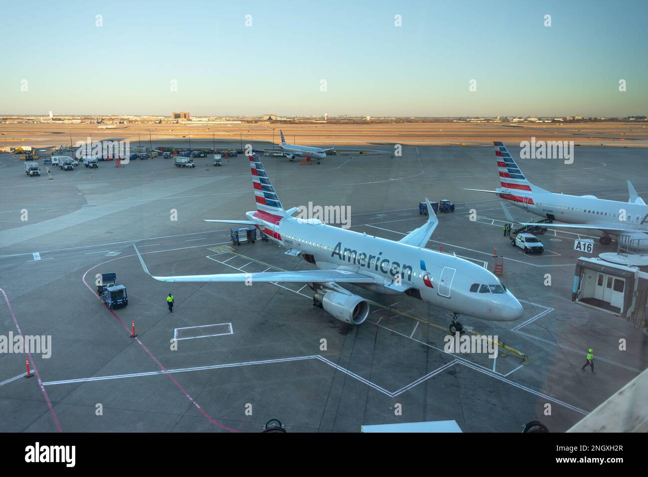 Deux avions américains stationnés à l'aéroport international DFW avec la piste derrière pendant le coucher du soleil Banque D'Images