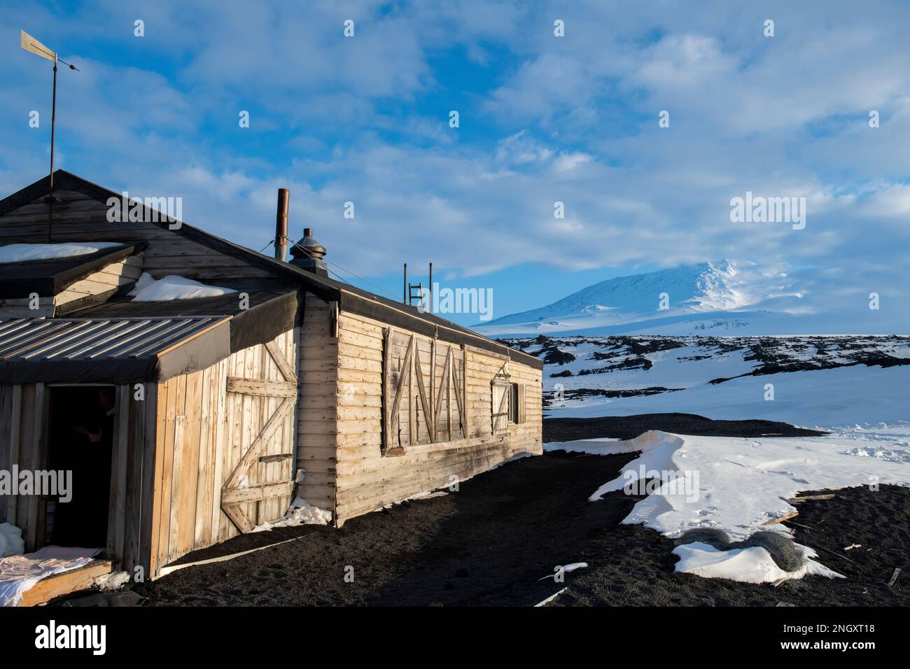 Antarctique, mer de Ross, île de Ross, Cap Evans. Vue extérieure de la cabane historique de Scott avec le mont Erebus au loin. Banque D'Images