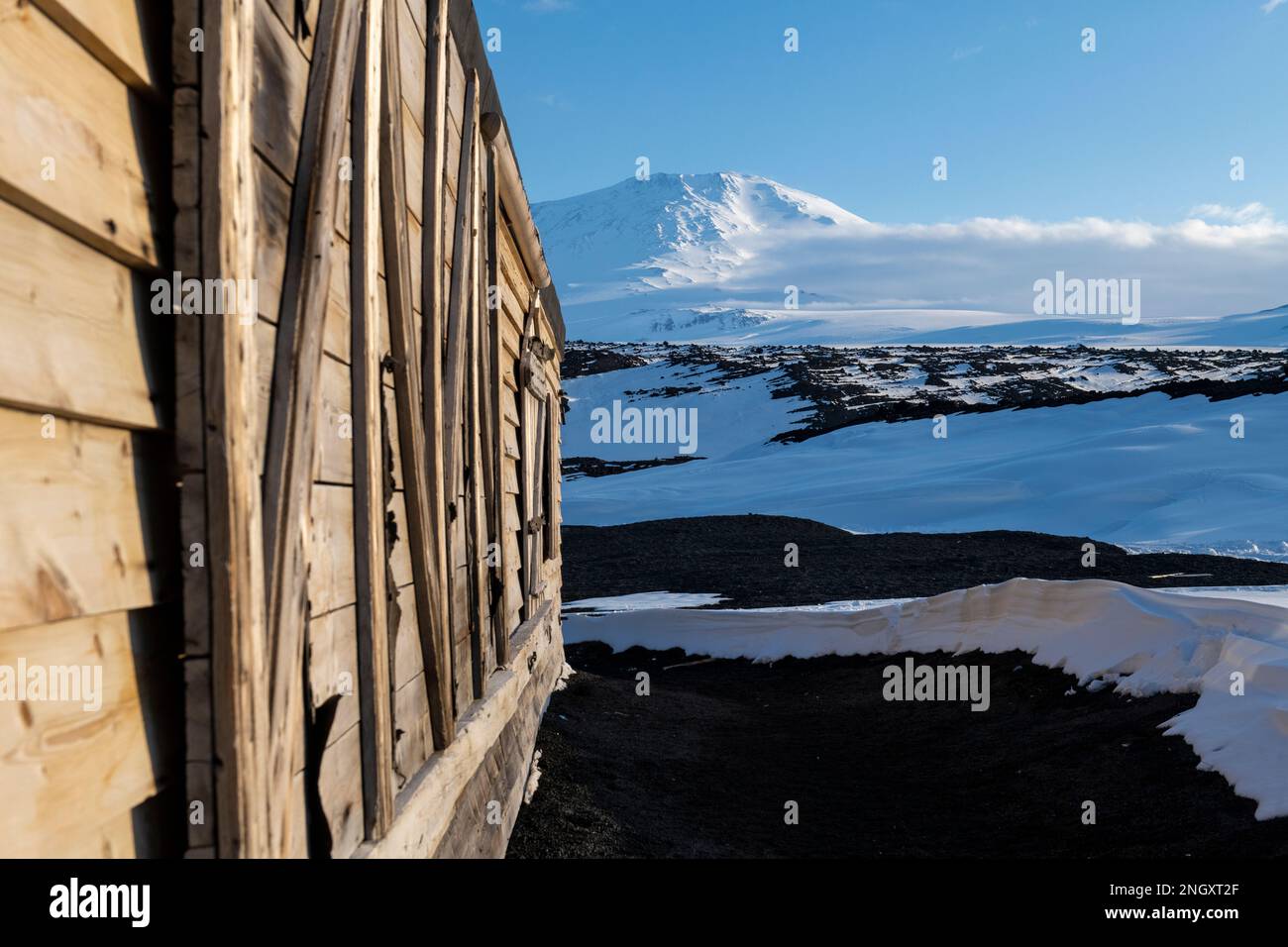 Antarctique, mer de Ross, île de Ross, Cap Evans. Vue extérieure de la cabane historique de Scott avec le mont Erebus au loin. Banque D'Images
