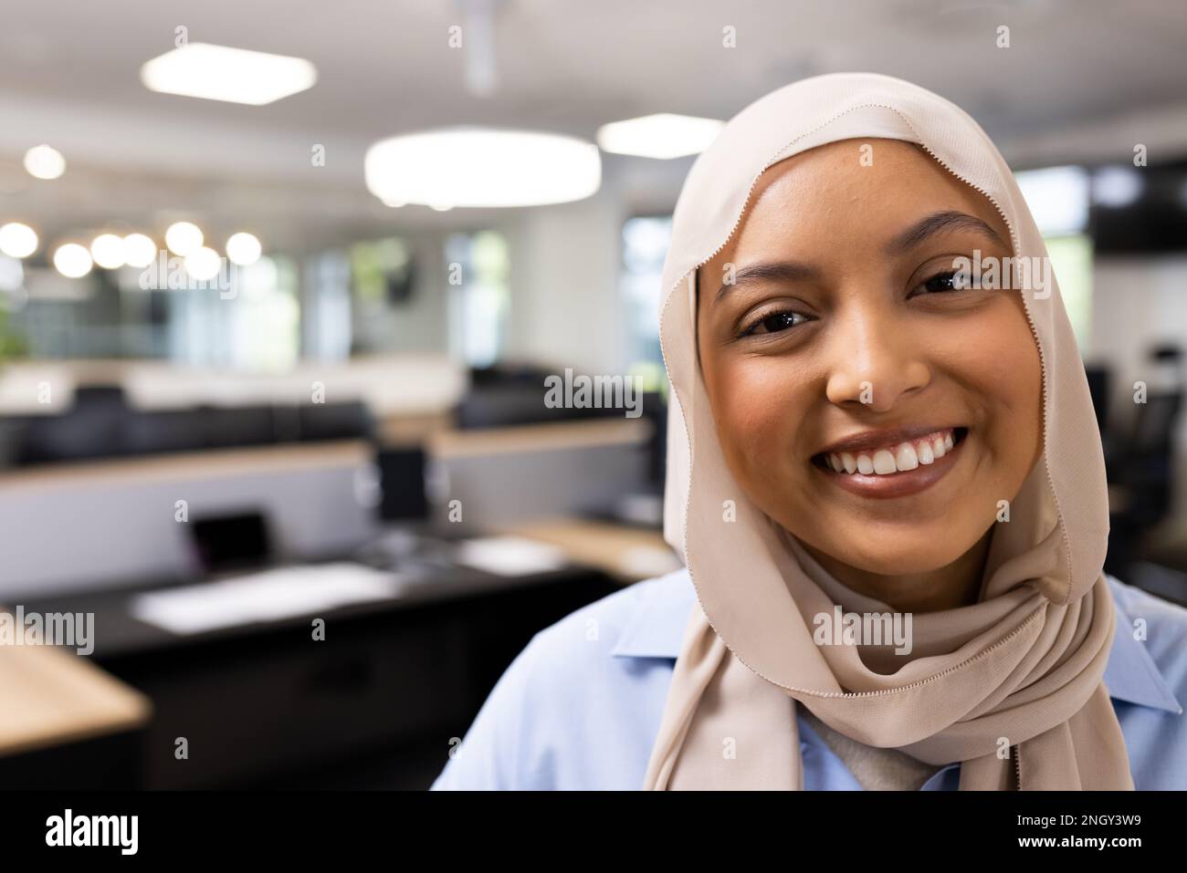 Bonne femme d'affaires du Moyen-Orient dans le hijab regardant la caméra dans le bureau Banque D'Images