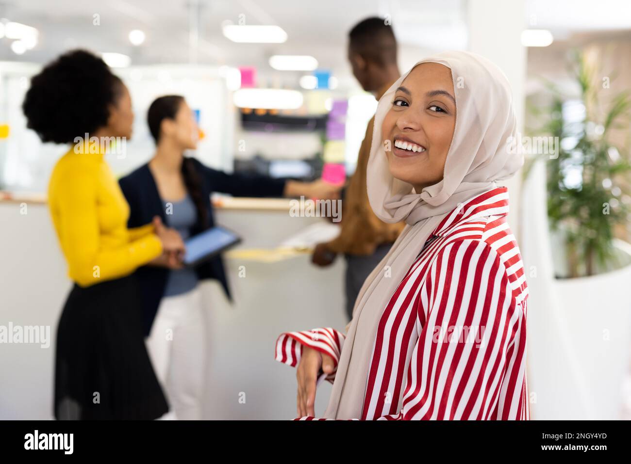 Une heureuse femme du Moyen-Orient dans le hijab souriant à la caméra dans le bureau Banque D'Images