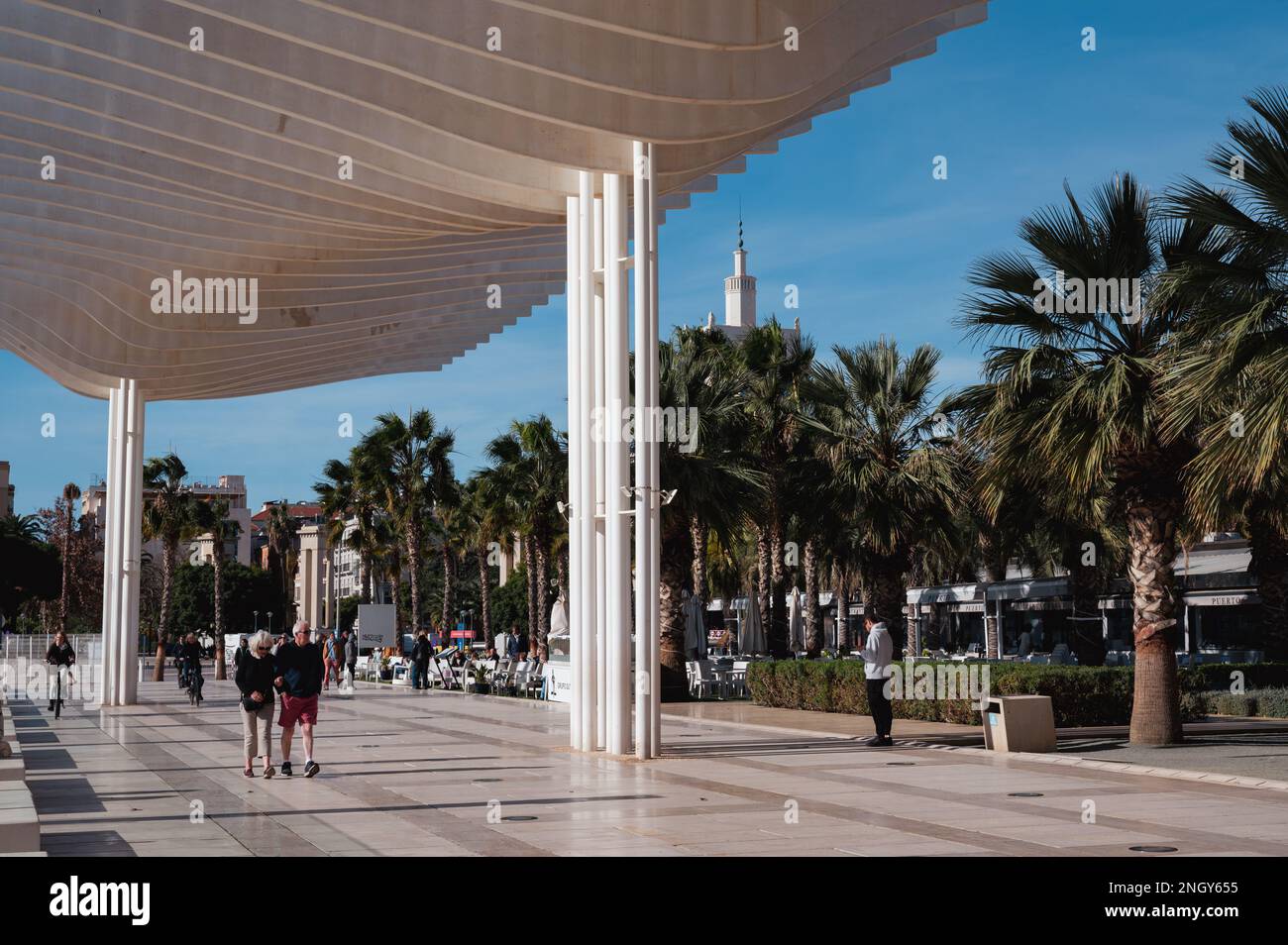 Malaga, Espagne - 16 janvier 2023: Personnes marchant sous les Pérgolas de la Victoria (espagnol pour les Pergolas de Victoria) à la jetée Banque D'Images Malaga, Espagne - 16 janvier 2023: Personnes marchant sous les Pérgolas de la Victoria (espagnol pour les Pergolas de Victoria) à la jetée Banque D'Images