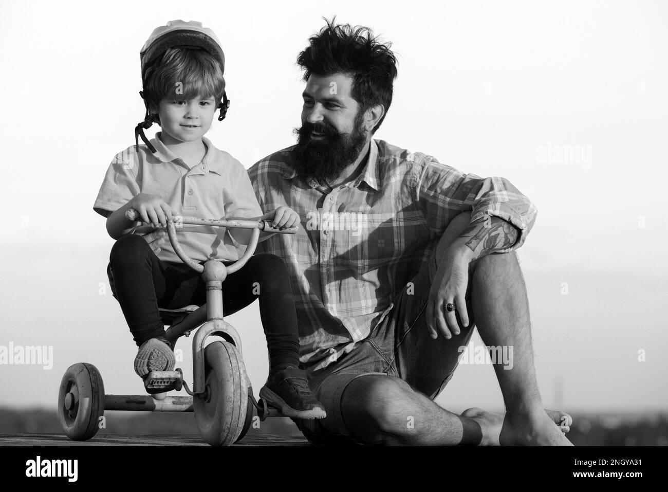 Père et fils. Papa aide son enfant à faire du vélo. Beau père enseignant fils à vélo Banque D'Images
