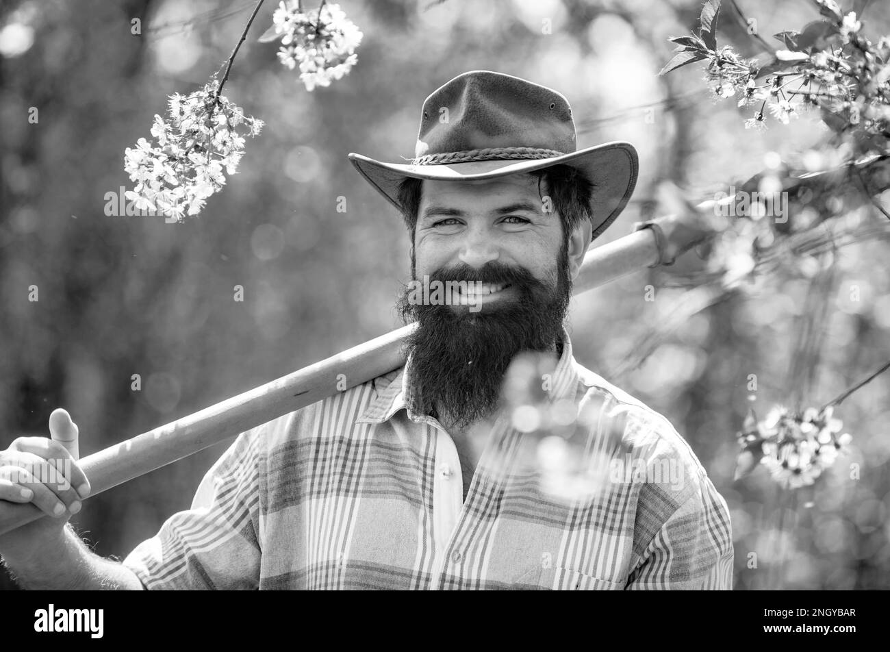 Bon jardinier travaille dans la cour avec des outils de jardin et ont du bon temps. Agriculteur travaillant sur le terrain. Printemps et loisirs. Banque D'Images