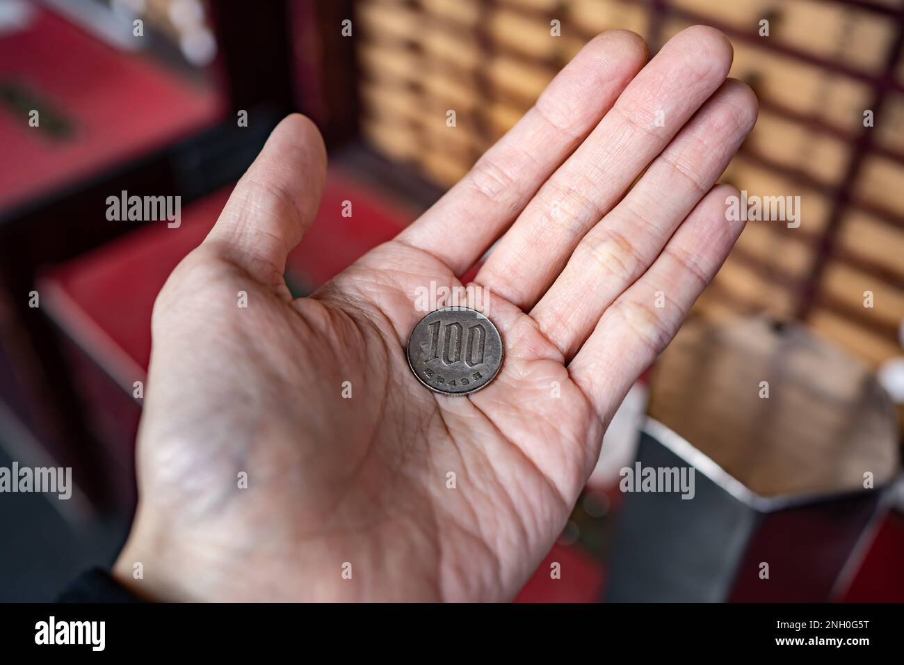 pièce de 100 yens dans la main des hommes Banque D'Images