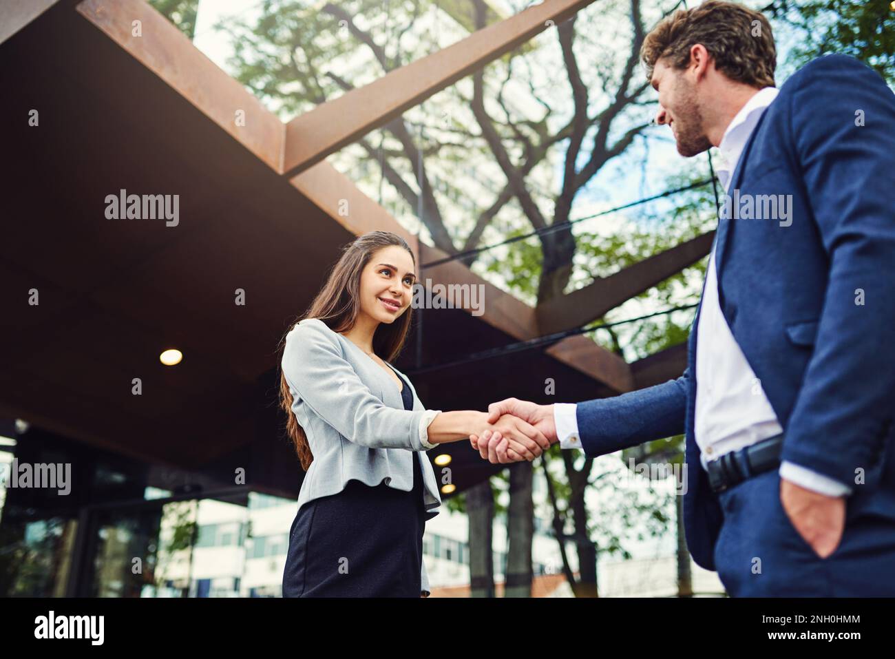Réunions d'affaires de partout. une femme d'affaires et un homme d'affaires qui se secouent les mains à l'extérieur. Banque D'Images